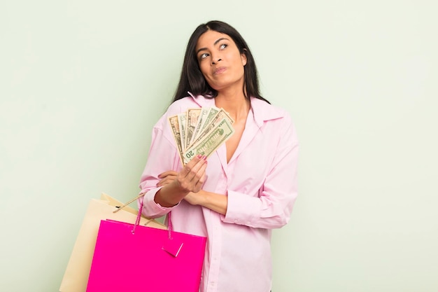 jeune jolie femme hispanique haussant les épaules, se sentant confuse et incertaine. concept de sacs à provisions