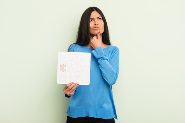 jeune jolie femme hispanique pensant, se sentant douteuse et confuse. notion de casse-tête