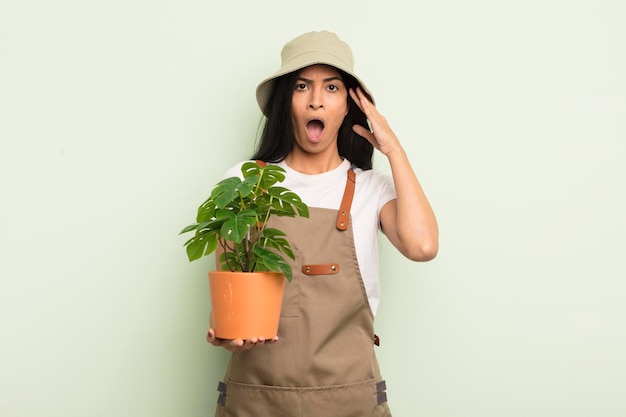 Jeune jolie femme hispanique à la recherche d'un concept d'agriculteur ou de jardinier heureux étonné et surpris