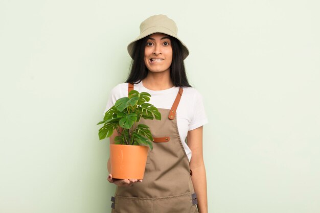 Jeune jolie femme hispanique à la recherche d'un concept d'agriculteur ou de jardinier perplexe et confus
