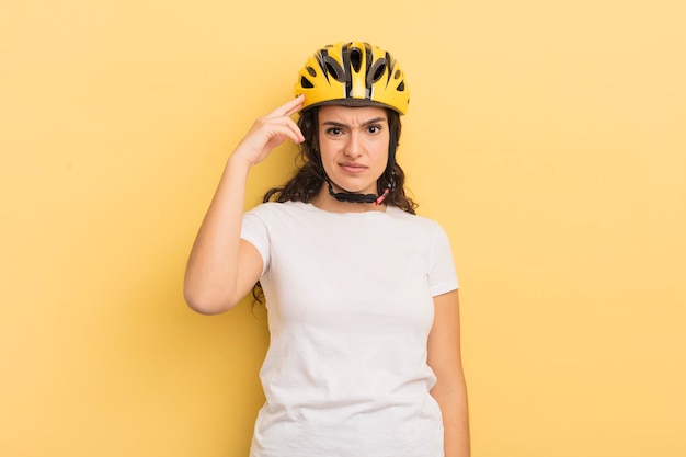 Jeune jolie femme hispanique se sentant confuse et perplexe montrant que vous êtes un concept de vélo fou