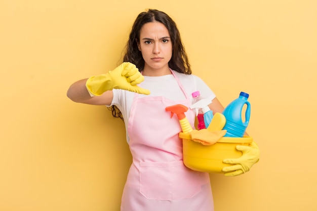 Jeune jolie femme hispanique se sentant croisée les pouces vers le bas les travaux ménagers un concept de produits propres