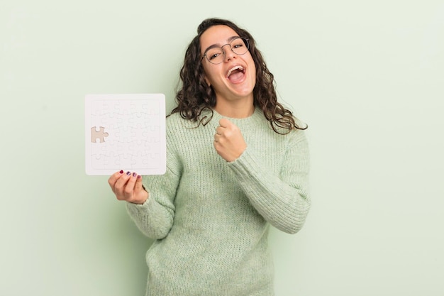 Jeune jolie femme hispanique se sentant heureuse et faisant face à un défi ou célébrant le concept de puzzle