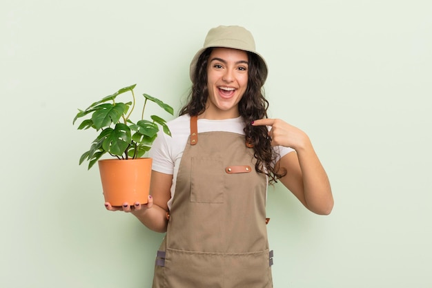 Jeune jolie femme hispanique se sentant heureuse et pointant vers soi avec un concept d'agriculteur ou de jardinier excité