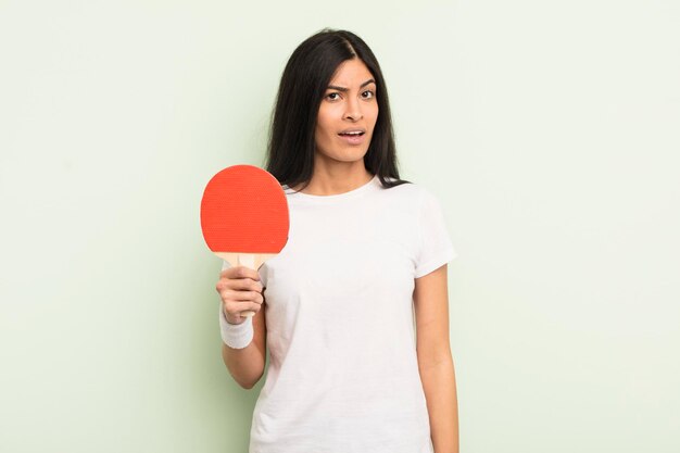 Jeune jolie femme hispanique se sentant perplexe et confuse concept de ping-pong