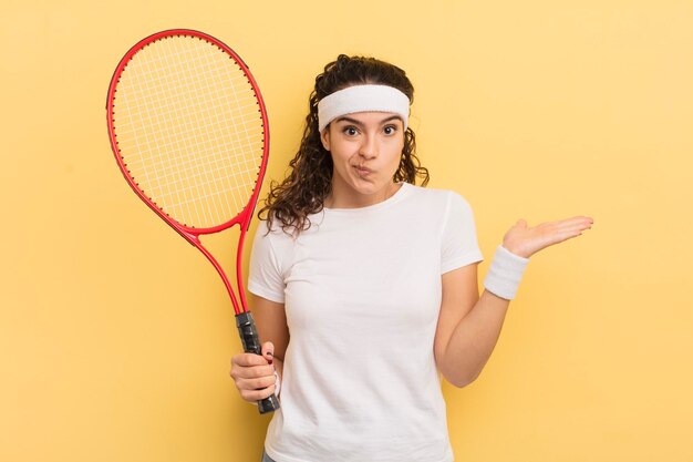 Jeune jolie femme hispanique se sentant perplexe et confuse et doutant du concept de tennis