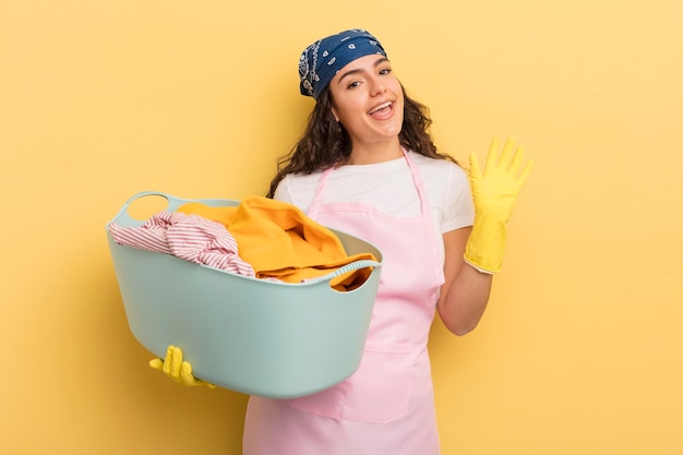 Jeune jolie femme hispanique souriant joyeusement en agitant la main accueillant et saluant vous laver et concept de vêtements