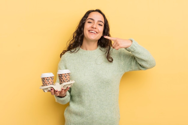 Jeune jolie femme hispanique souriant en toute confiance pointant vers son propre large sourire concept de café à emporter