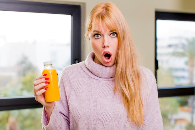 Jeune jolie femme avec un jus d'orange à l'intérieur de la maison