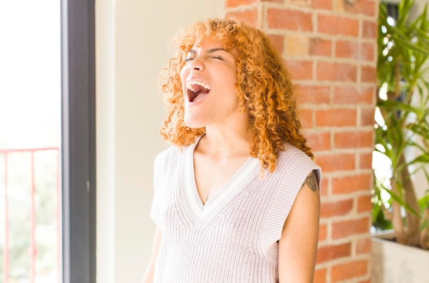 Jeune jolie femme latine aux cheveux roux dans une nouvelle maison cool