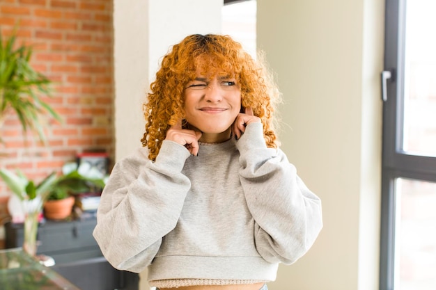 Jeune jolie femme latine aux cheveux roux dans une nouvelle maison cool