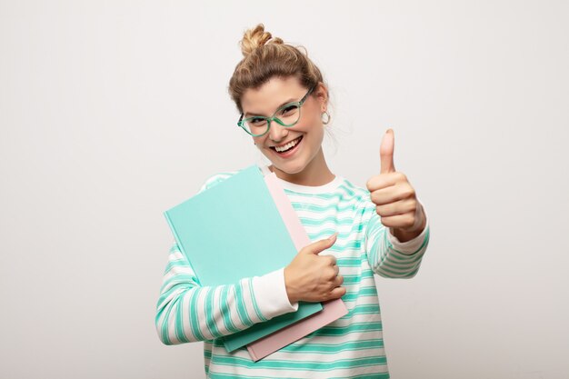 Jeune jolie femme latine contre un mur plat avec des livres. concept étudiant