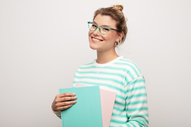 Jeune jolie femme latine contre un mur plat avec des livres. concept étudiant