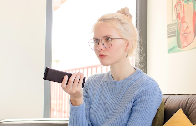 Jeune jolie femme à la maison à l'aide d'un téléphone