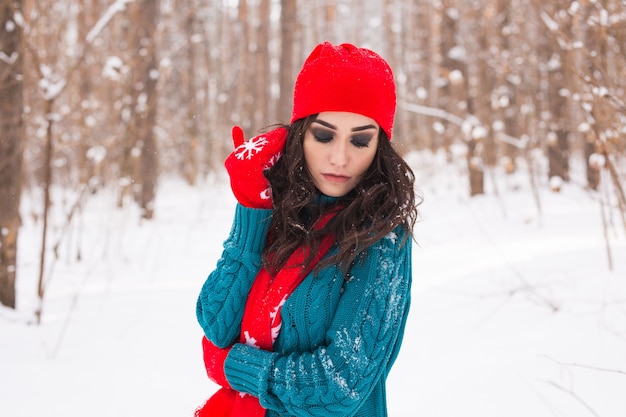 Jeune jolie femme marchant dans le parc enneigé d'hiver à la journée ensoleillée