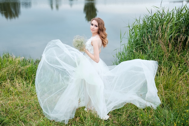 Jeune jolie femme (mariée) en robe de mariée blanche à l'extérieur, coiffure