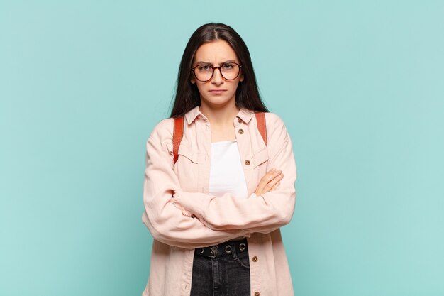 Jeune jolie femme mécontente et déçue, l'air sérieuse, agacée et en colère contre les bras croisés. concept d'étudiant