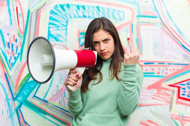 Photo jeune jolie femme avec un mégaphone contre le mur de graffitis