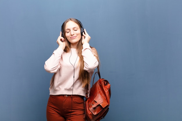 Jeune jolie femme sur un mur bleu avec un espace de copie