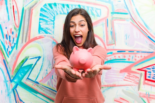 Jeune jolie femme avec un mur de graffitis tirelire