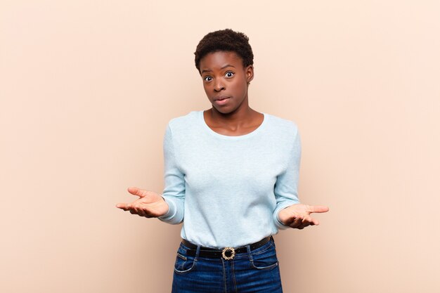 Jeune jolie femme noire à la bouche ouverte et étonnée, choquée et étonnée d'une incroyable surprise