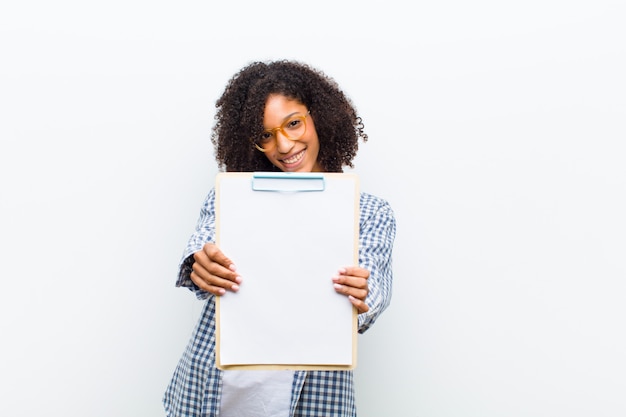 Jeune jolie femme noire avec une feuille de papier contre blanc