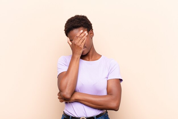 Jeune jolie femme noire à la recherche de stress couvrant le visage avec la main