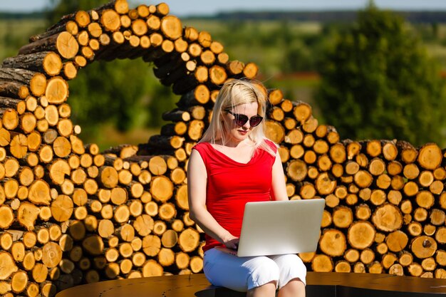 Jeune jolie femme avec un ordinateur portable sur le banc dans un parc