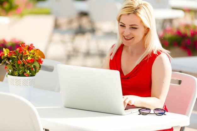Jeune jolie femme avec un ordinateur portable sur le banc dans un parc