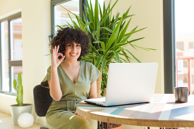 Jeune jolie femme avec un ordinateur portable sur une table