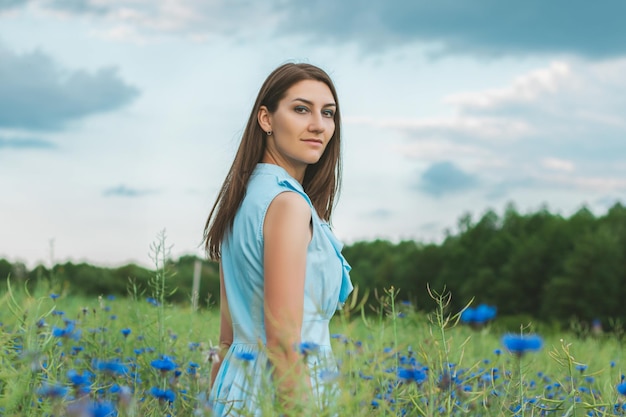 Jeune jolie femme parmi le champ de beaux bleuets