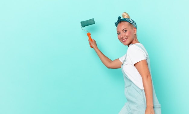 Jeune jolie femme peignant un mur avec un rouleau