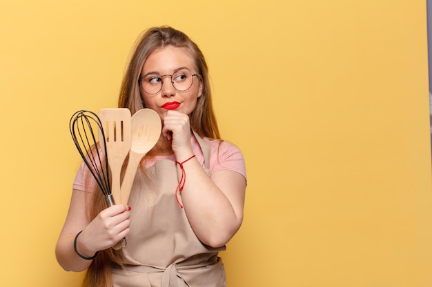 Jeune jolie femme. penser ou douter du concept de cuisine du chef d'expression