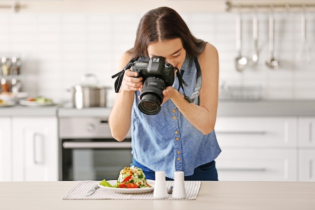 Jeune jolie femme photographiant de la nourriture dans la cuisine