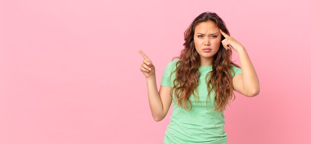 Photo jeune jolie femme et pointant vers l'espace de copie