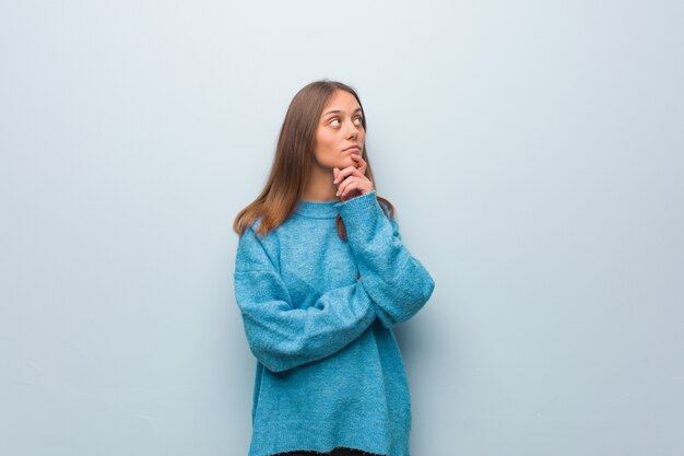 Jeune jolie femme portant un pull bleu doutant et confus