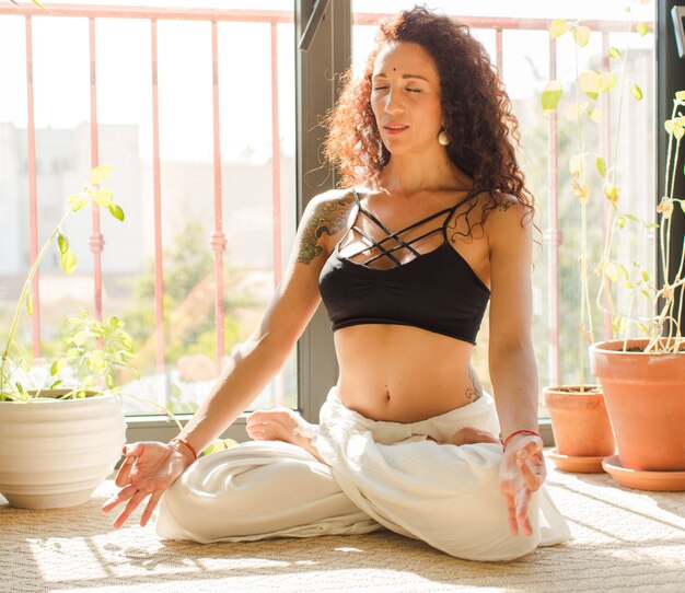 Jeune jolie femme pratiquant le yoga à l'intérieur.