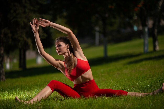 Jeune jolie femme pratiquant le yoga en plein air