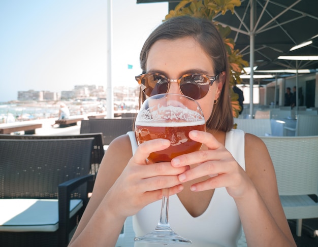 Jeune jolie femme prenant une bière dans un restaurant