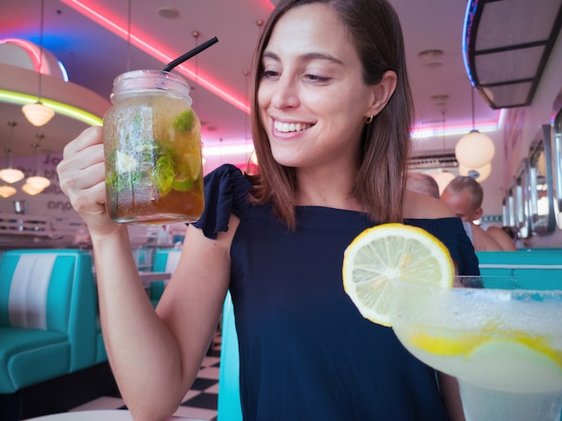 Jeune jolie femme prenant un cocktail mojito frais dans un restaurant