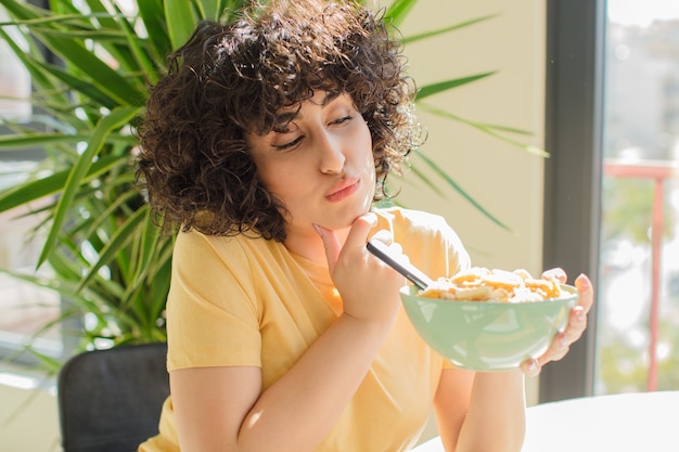 Jeune et jolie femme prenant son petit déjeuner à la maison.