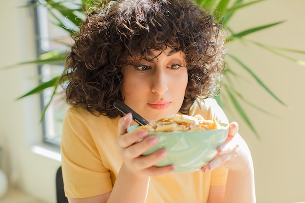 Jeune jolie femme prenant son petit déjeuner à la maison