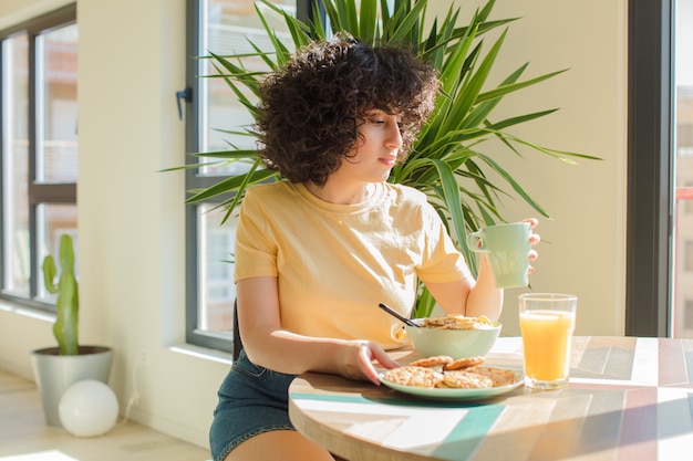 Jeune jolie femme prenant son petit déjeuner à la maison