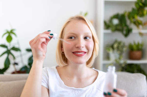 Jeune jolie femme recevant un traitement spécial pour la peau à la maison Belle fille appliquant du sérum pour les yeux Peau lisse sans rides