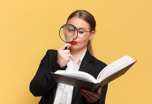 Jeune jolie femme recherchant avec un livre et une loupe recherchant dans un concept de livre