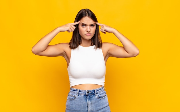 Jeune jolie femme avec un regard sérieux et concentré, un brainstorming et une réflexion sur un problème difficile