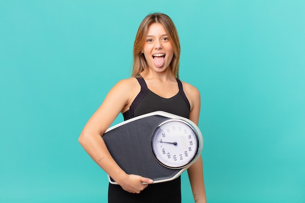 Jeune jolie femme de remise en forme avec une attitude joyeuse et rebelle, plaisantant et tirant la langue