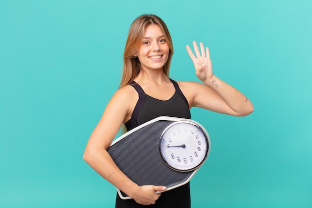 Jeune jolie femme de remise en forme souriante et semblant amicale, montrant le numéro quatre