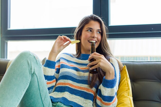 Jeune jolie femme reposante sur le canapé à l'intérieur