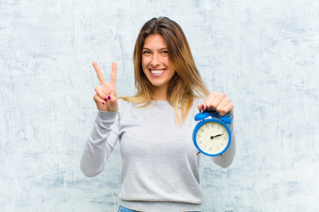 Jeune jolie femme avec un réveil contre le mur de grunge